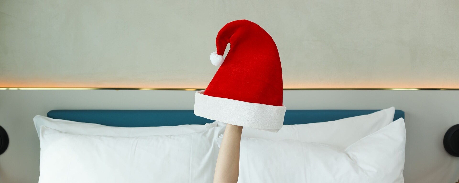 An arm in a bed with a Santa Claus hat 