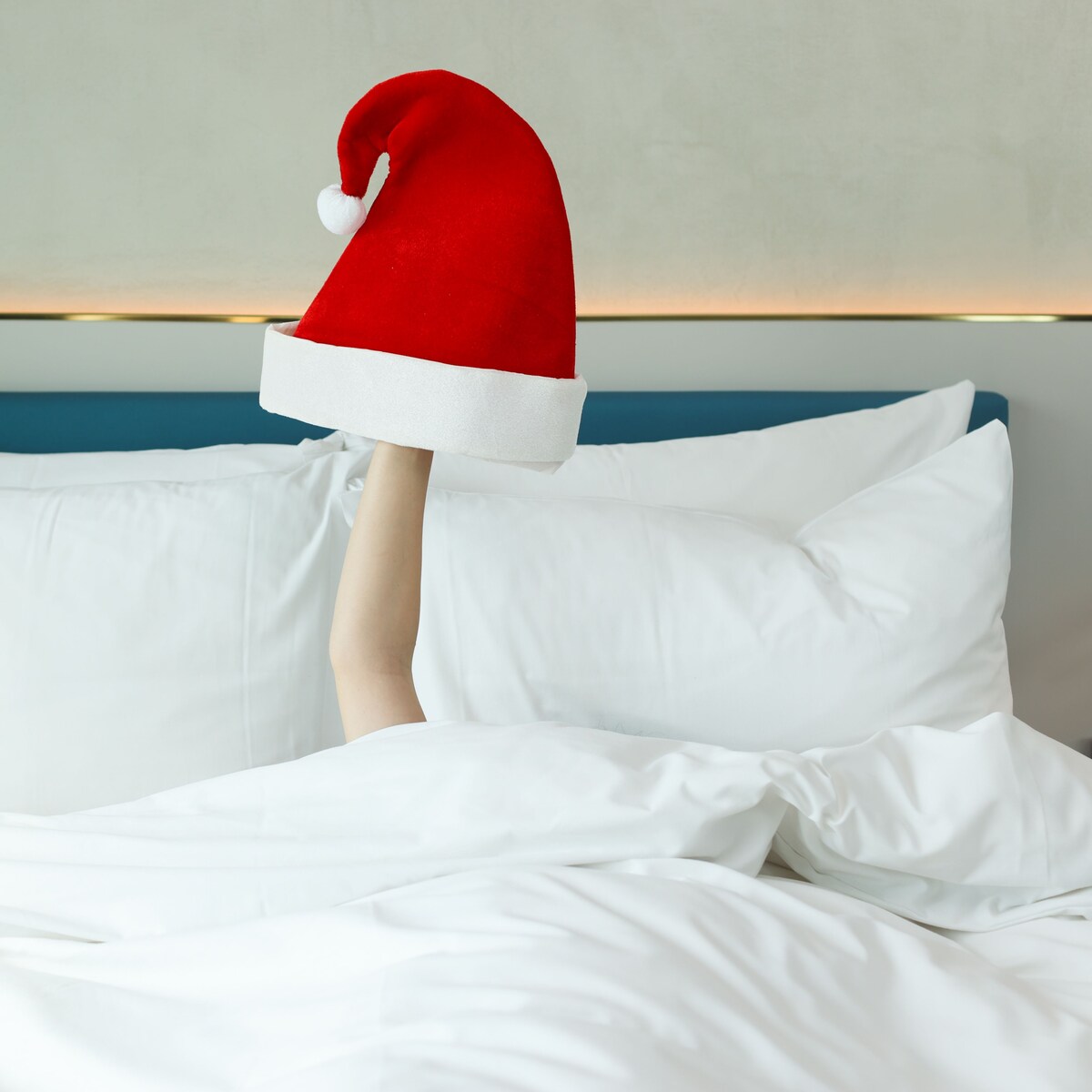 An arm in a bed with a Santa Claus hat 