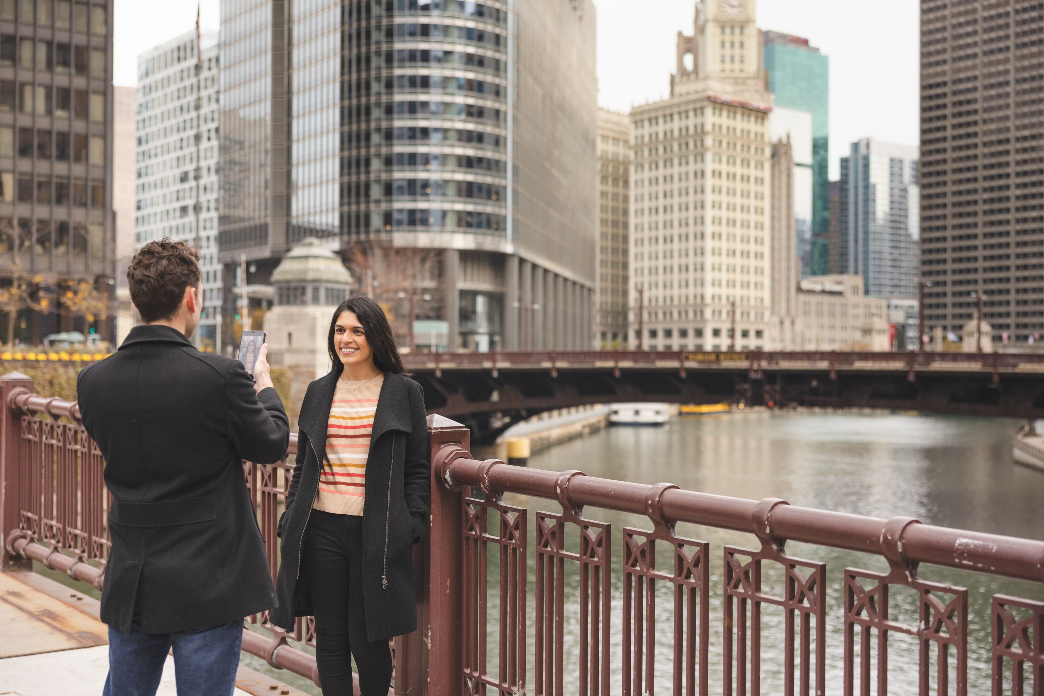 A person takes a photo of another person on a bridge