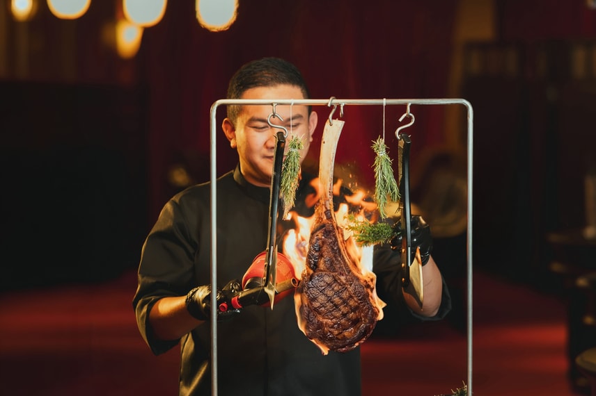 Chef serving hanging meat display to guests