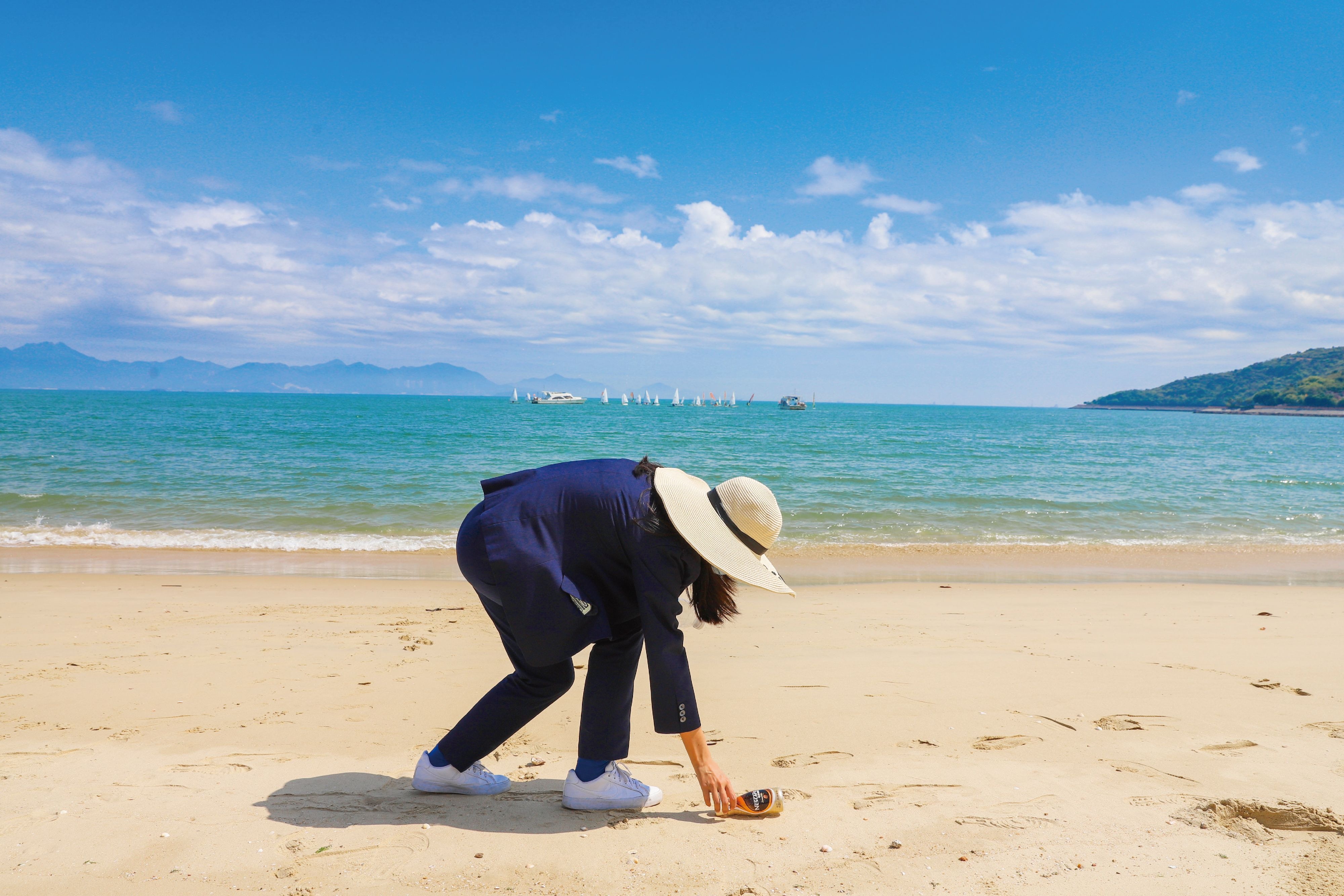 A woman is bending over to pick up the trash.