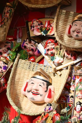 Collection of Japanese masks that depict smiling faces and are mounted on straw baskets