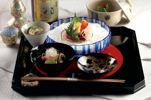 Tray with three bowls of Japanese food, chopsticks and a bottle of sake