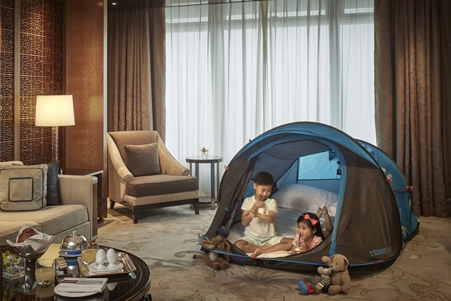 Two kids in a tent within a hotel guest room
