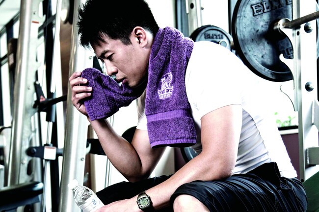 A man in gym gear wipes his face with a towel