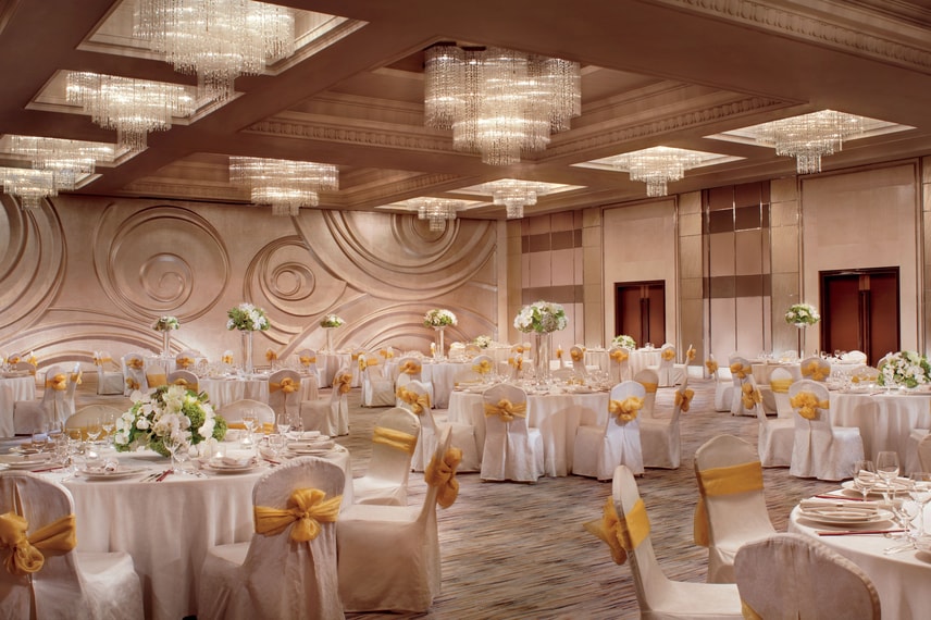 Ballroom reception with white tablecloths and chair covers, white and green floral centerpieces and yellow chair sashes