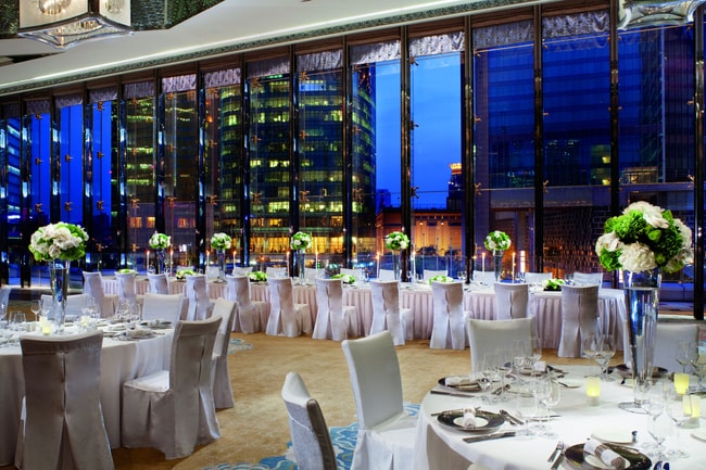 Wedding reception in a large space with tall ceilings, floor-to-ceiling windows and green-and-white florals