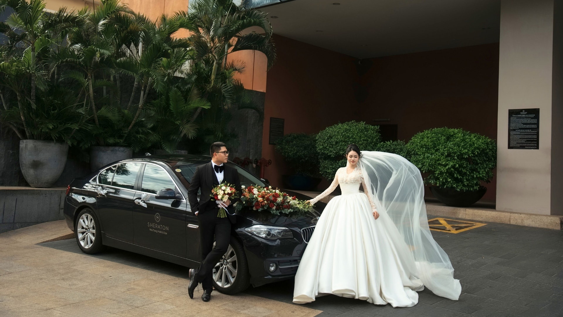 Bride and groom with car at entrance