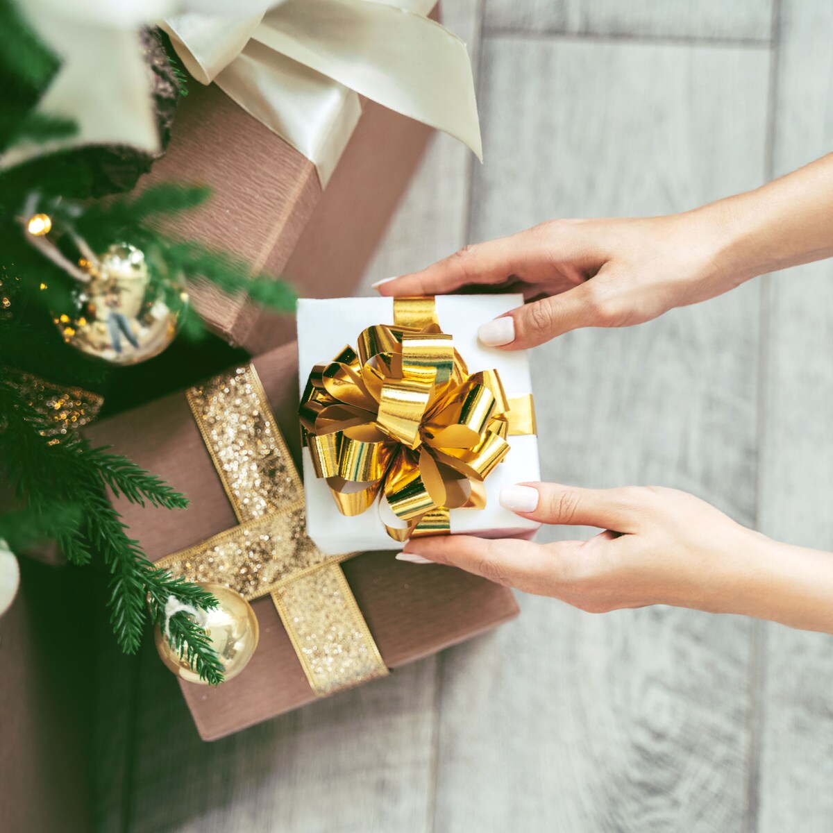 Soft woman hands putting gift box under the Christmas tree