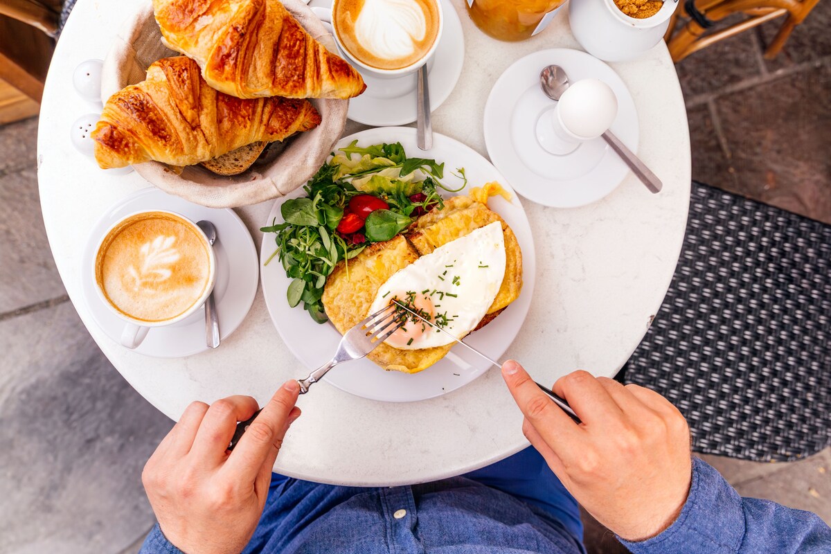 Man eating Croque Madame in a cafe, personal perspective view, Paris, France