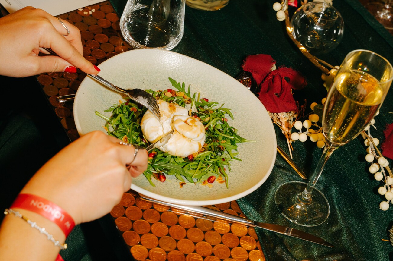 Person cutting burrata with champagne
