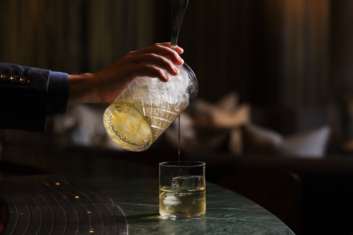 调酒师将饮料倒入装有冰块的杯中。