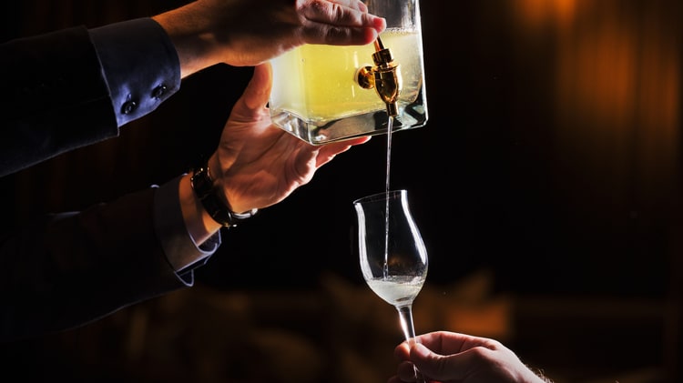 将黄色的酒液从醒酒器倒入杯中。